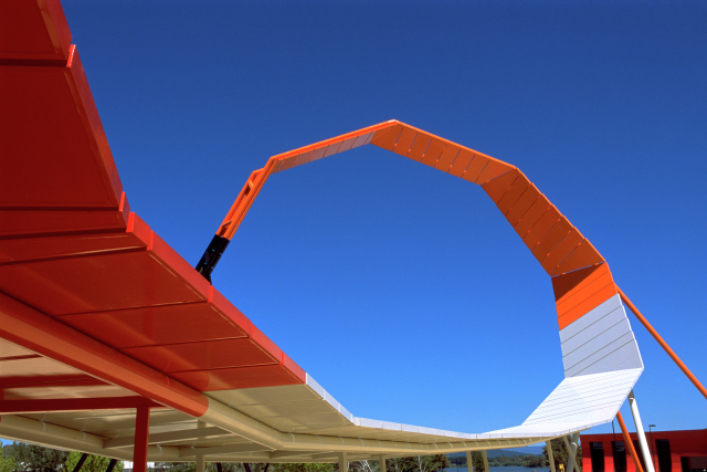 A looping white and orange steel structure against blue sky.
