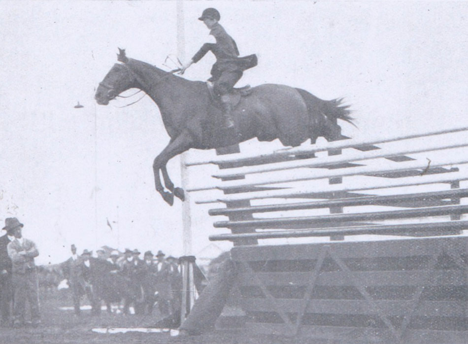 Woman jumping horse over large fence